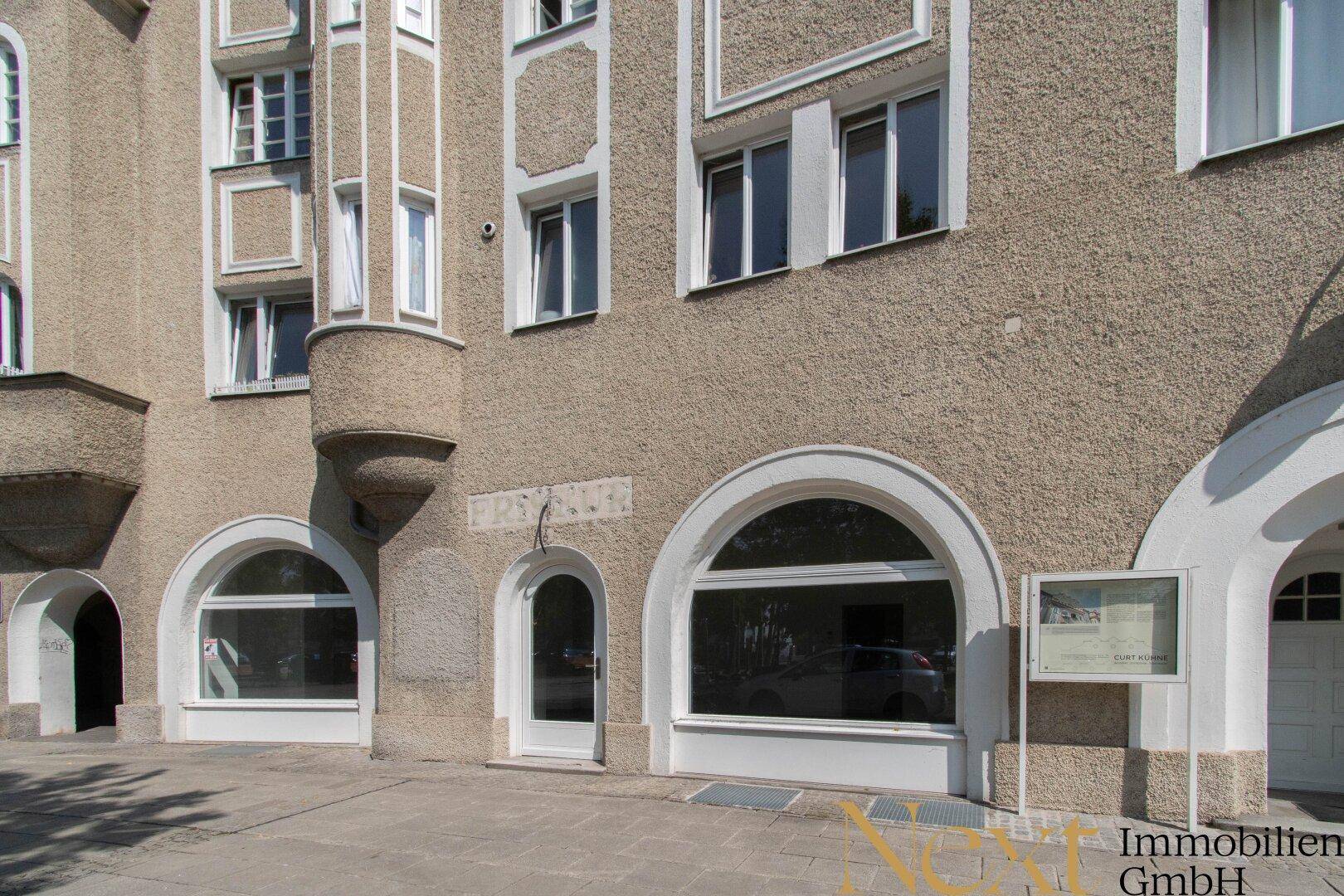 Historische Fassade eines Gebäudes mit großen Rundbogenfenstern und Eingangsbereichen.