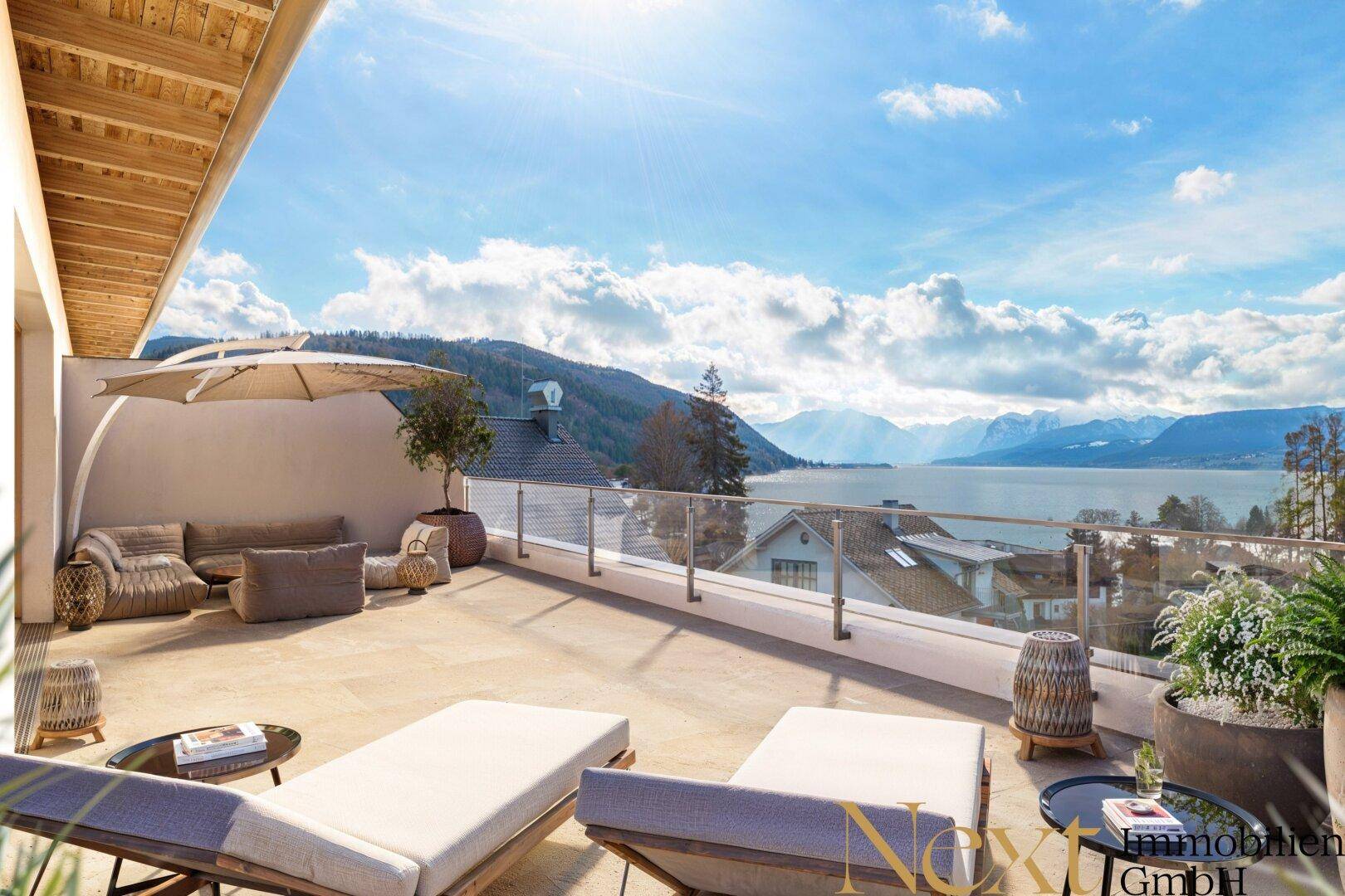 Großzügige Sonnenterrasse mit bequemen Liegen und atemberaubendem Blick auf den See und die Berge.