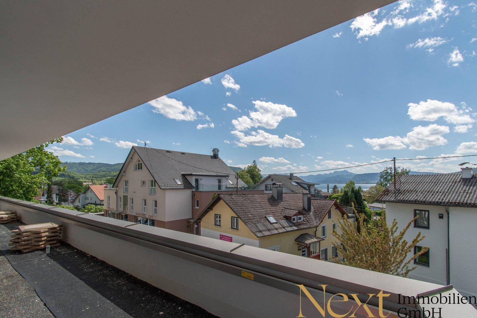 Weitläufiger Ausblick von der Terrasse über Dächer, See und die umliegende Berglandschaft.