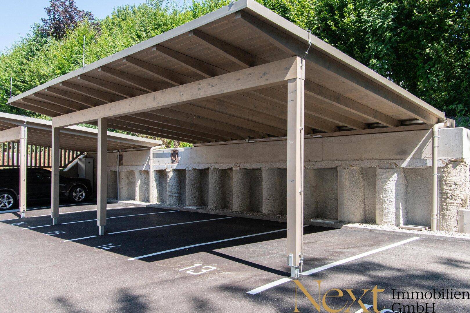 Überdachte Parkplätze unter einem Carport mit Holzkonstruktion, gut gepflegt und funktional.
