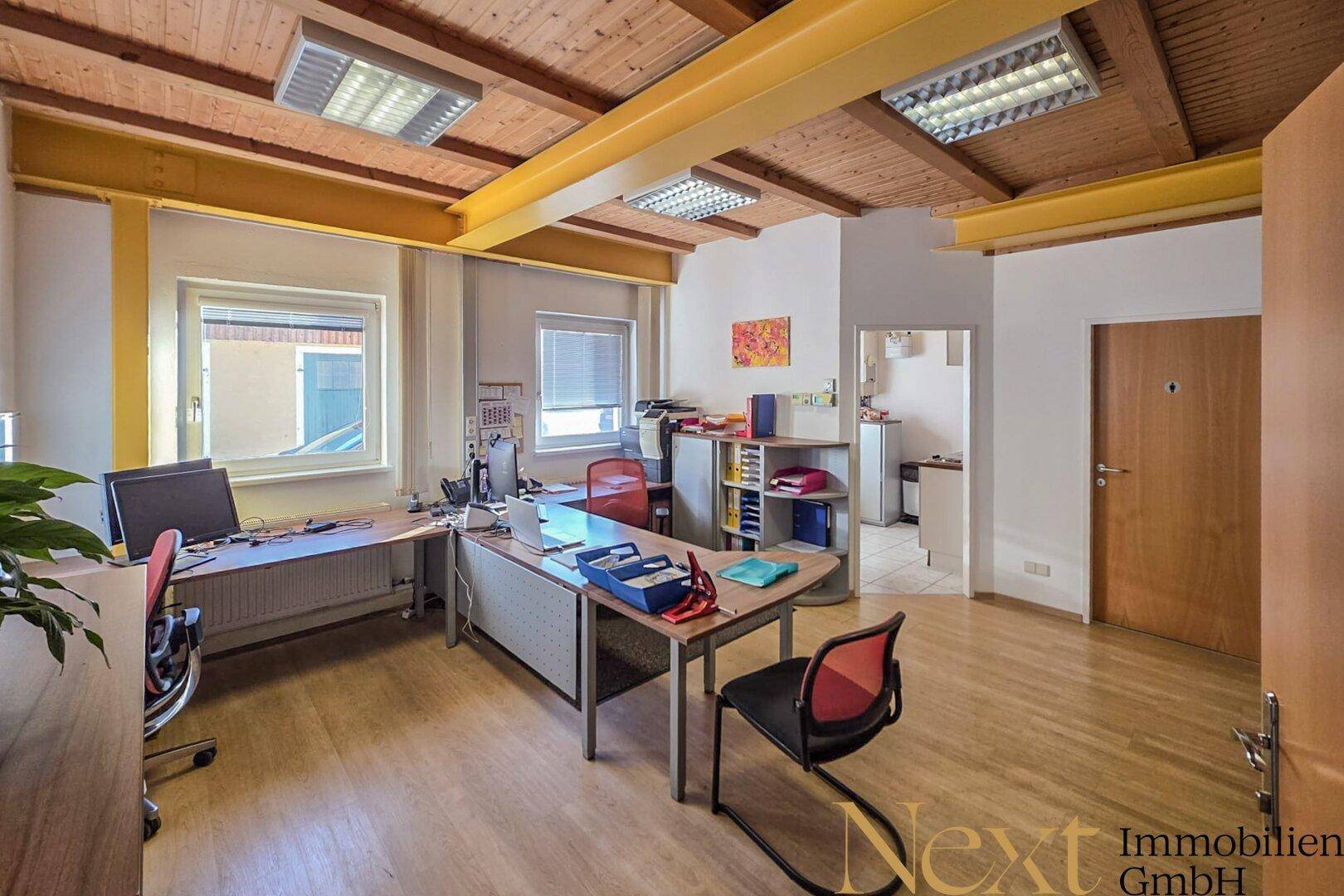 Geräumiges Büro mit mehreren Arbeitsplätzen, Holzbalkendecke und natürlichem Lichteinfall.