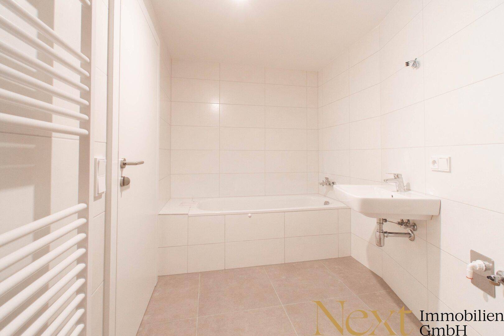 Modernes Badezimmer mit Badewanne, Einzelwaschbecken und beheiztem Handtuchhalter.