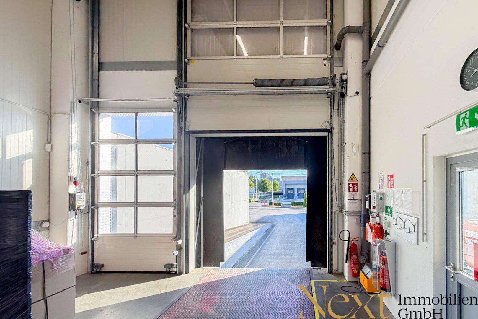 Detailansicht eines großen Rolltors zur Laderampe, mit sichtbaren Sicherheitsausrüstungen wie Feuerlöschern.