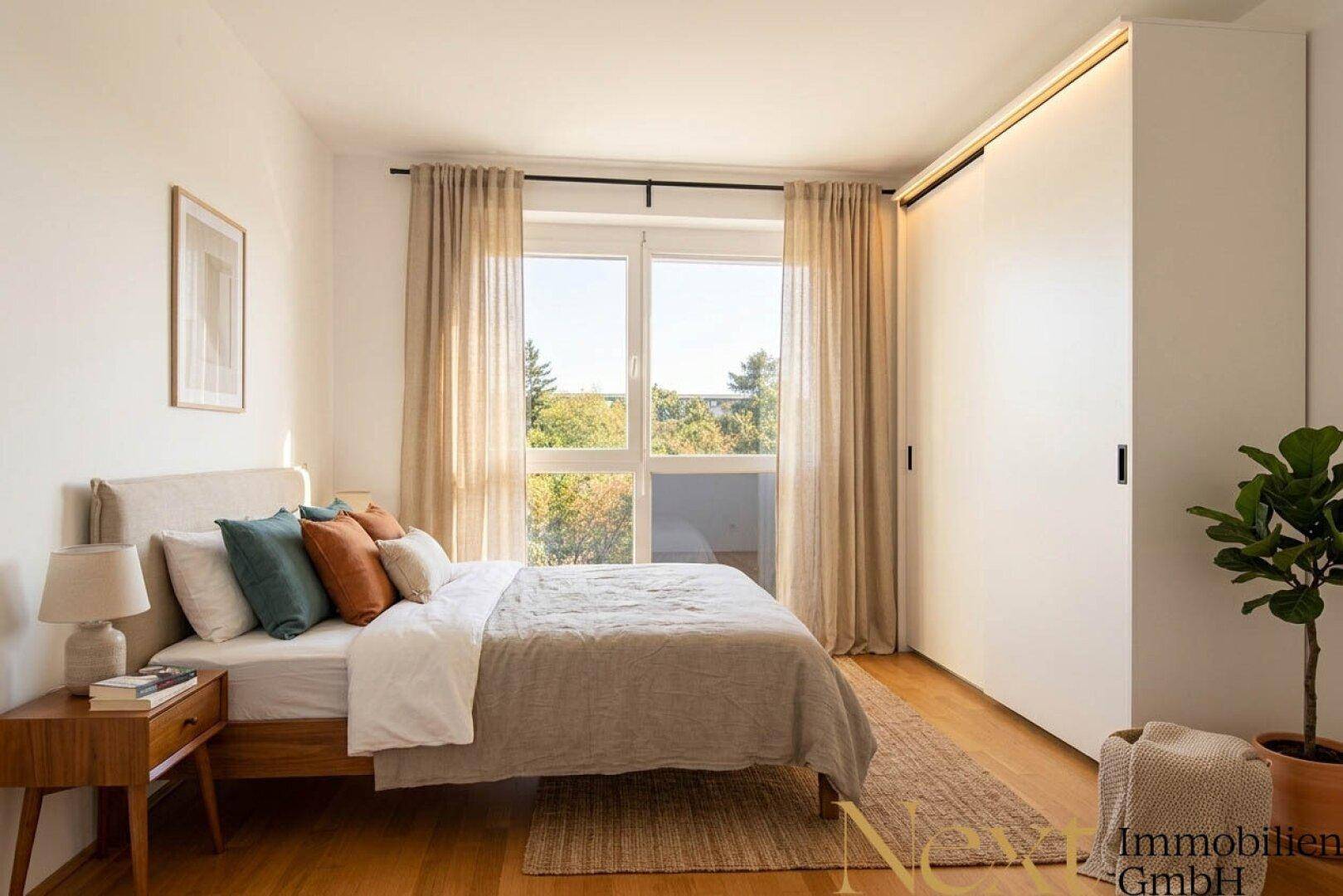 Gemütliches Schlafzimmer mit Doppelbett, Holzboden und großem Fenster mit Blick ins Grüne.