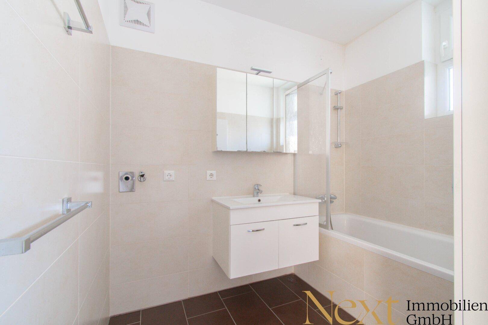 Modernes Badezimmer mit Badewanne, Duschwand, Einzelwaschbecken und Spiegelschrank.