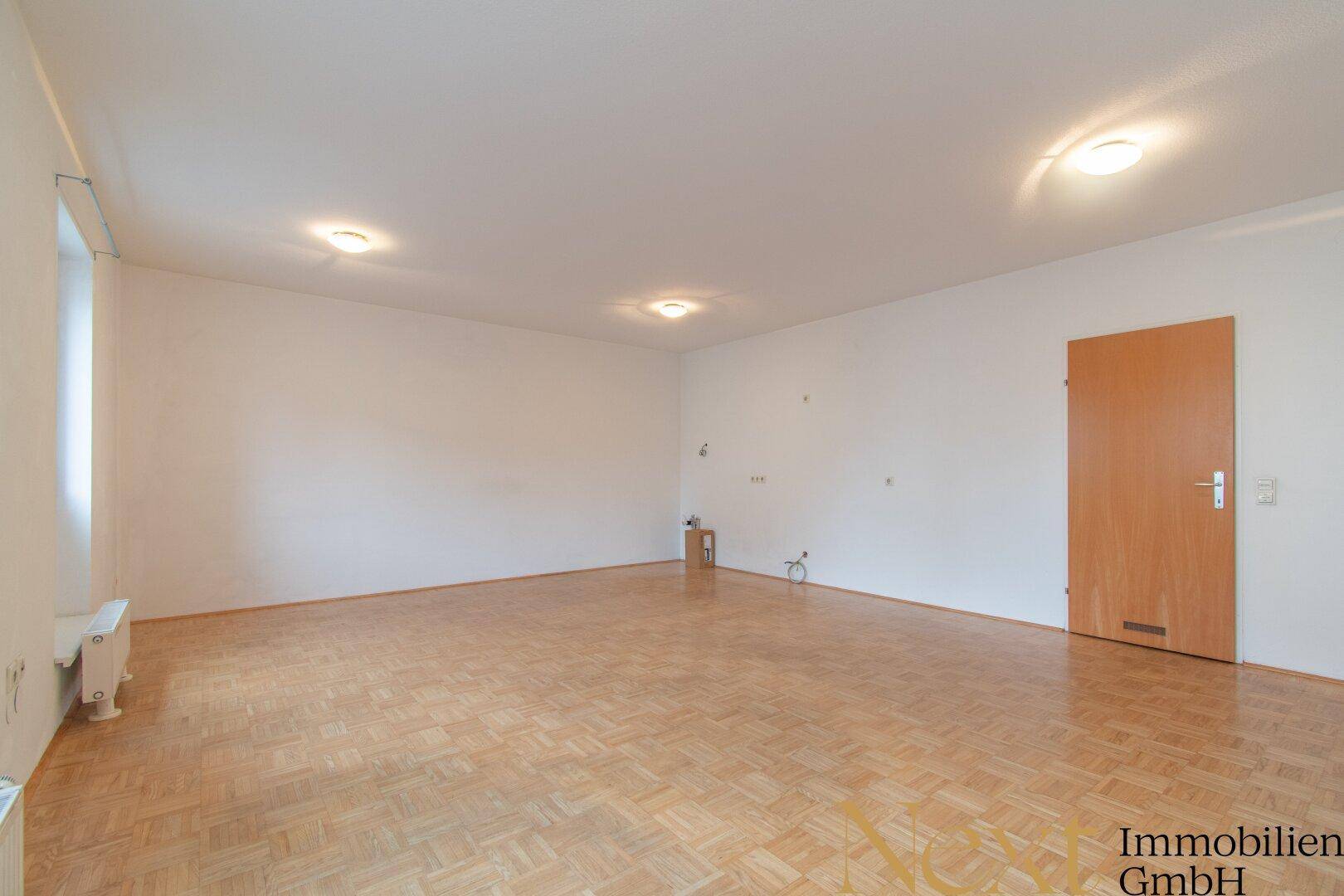 Leerer Raum mit hellem Holzparkettboden und weißen Wänden, bereit zur individuellen Gestaltung.