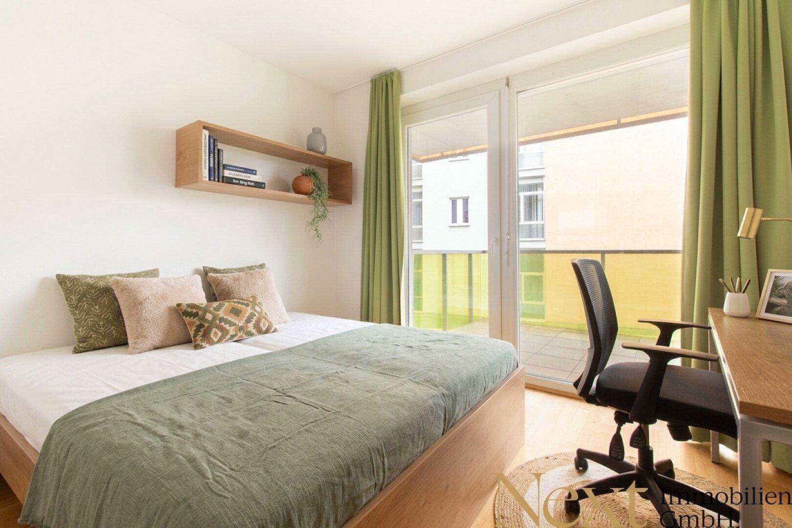 Helles Schlafzimmer mit Doppelbett, Schreibtisch und direktem Zugang zu einem Balkon mit Grünblick.