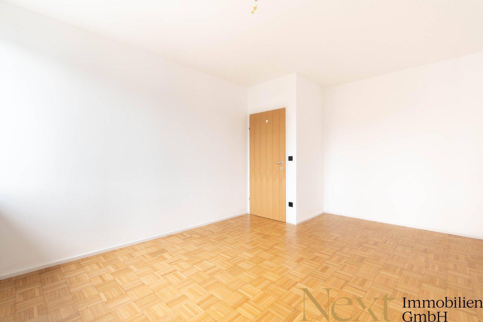 Leeres Schlafzimmer mit Parkettboden und weiß gestrichenen Wänden, ideal für individuelle Einrichtung.