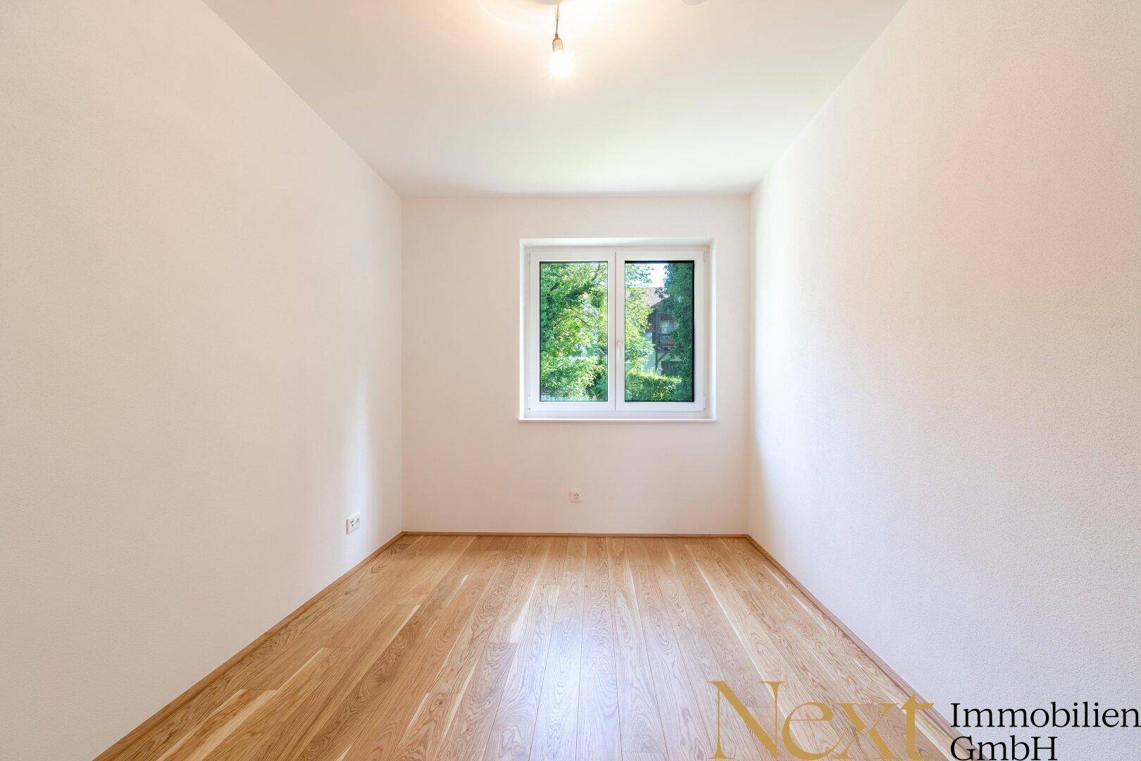 Helles, unmöbliertes Zimmer mit Holzboden und einem großen Fenster, ideal als Schlafzimmer.