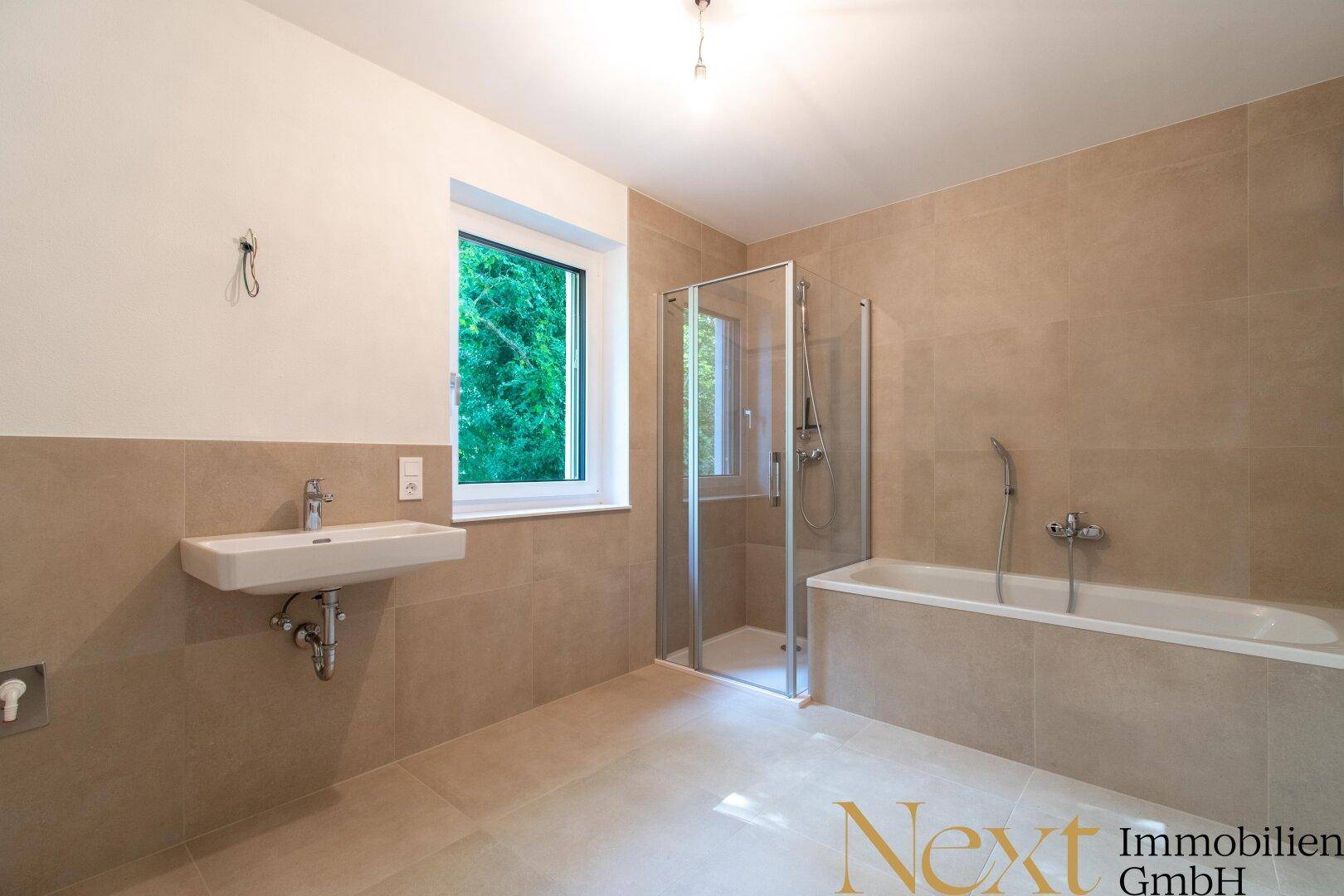 Modernes Badezimmer mit beigefarbenen Fliesen, Dusche, Badewanne und Fenster.