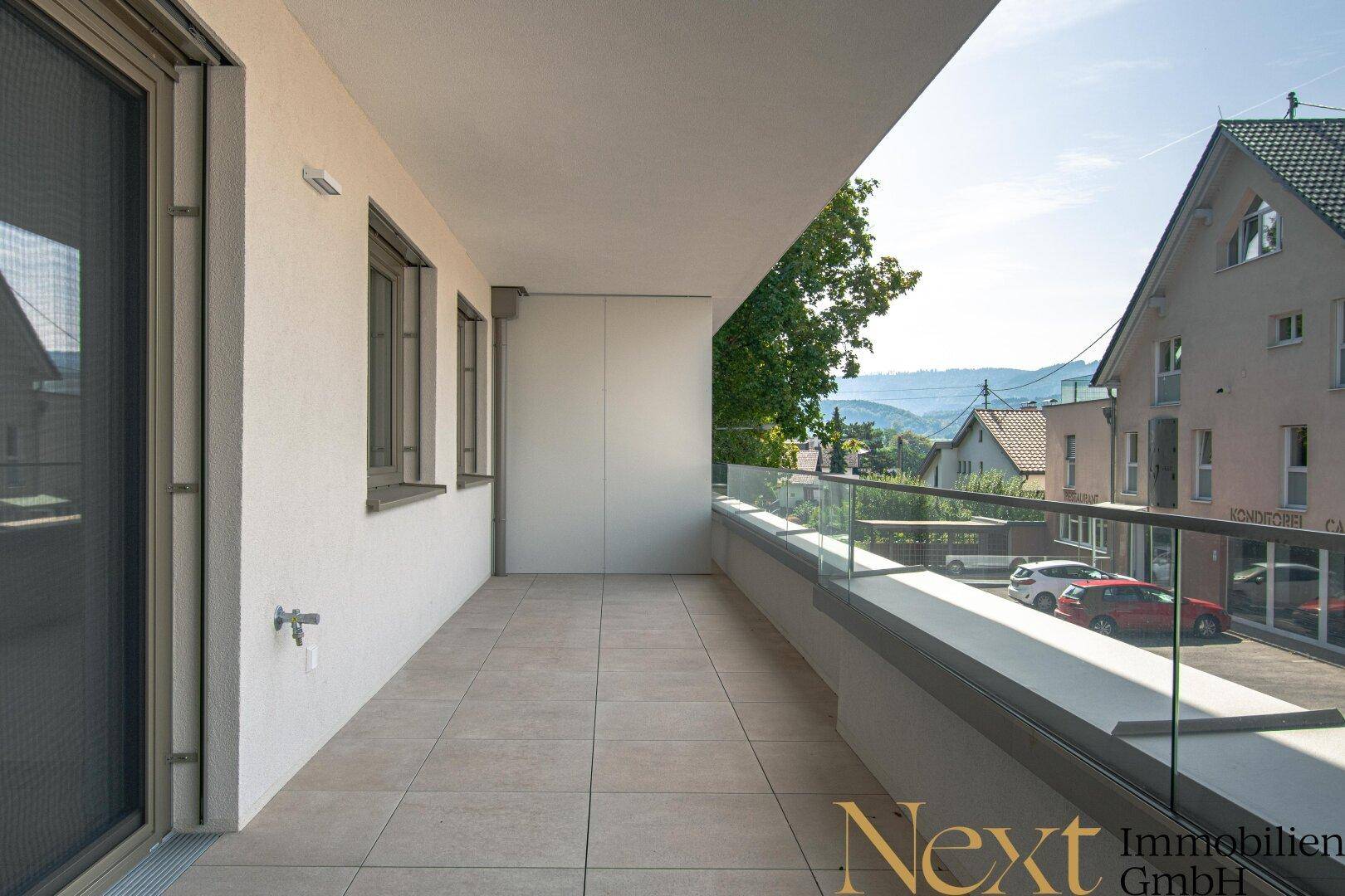Heller Balkon mit modernen Fliesen und Glasbrüstung, bereit für individuelle Gestaltung.