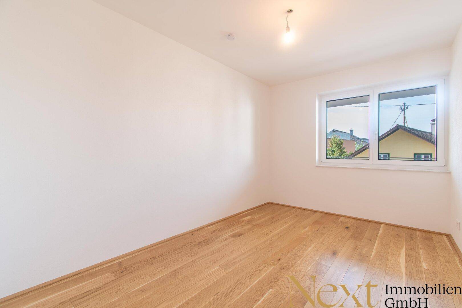 Ruhiges Schlafzimmer mit hellem Holzfußboden und Fenster, das viel Tageslicht hereinlässt.