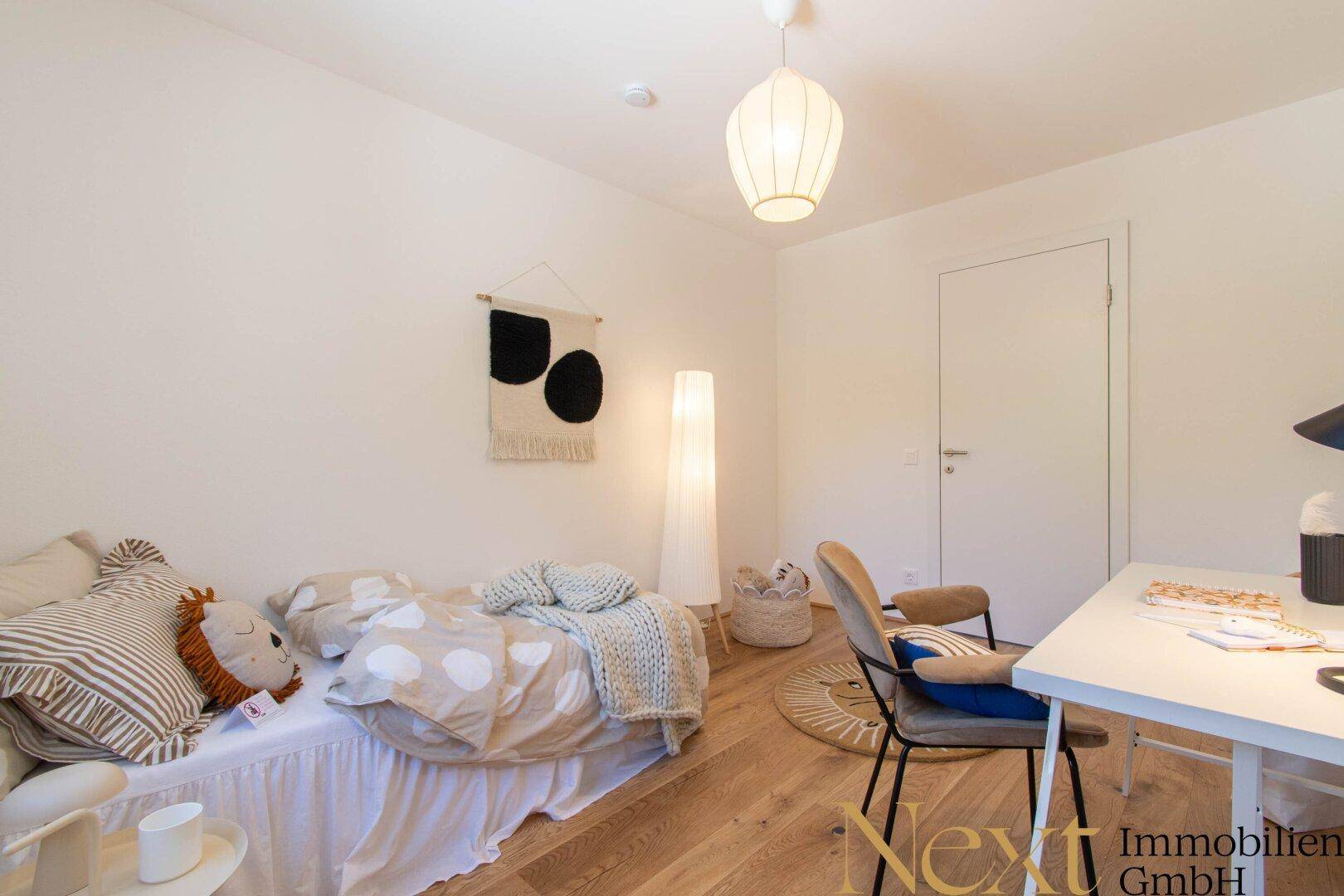 Helles Zimmer mit Holzboden, Einzelbett und modernem Schreibtischbereich.