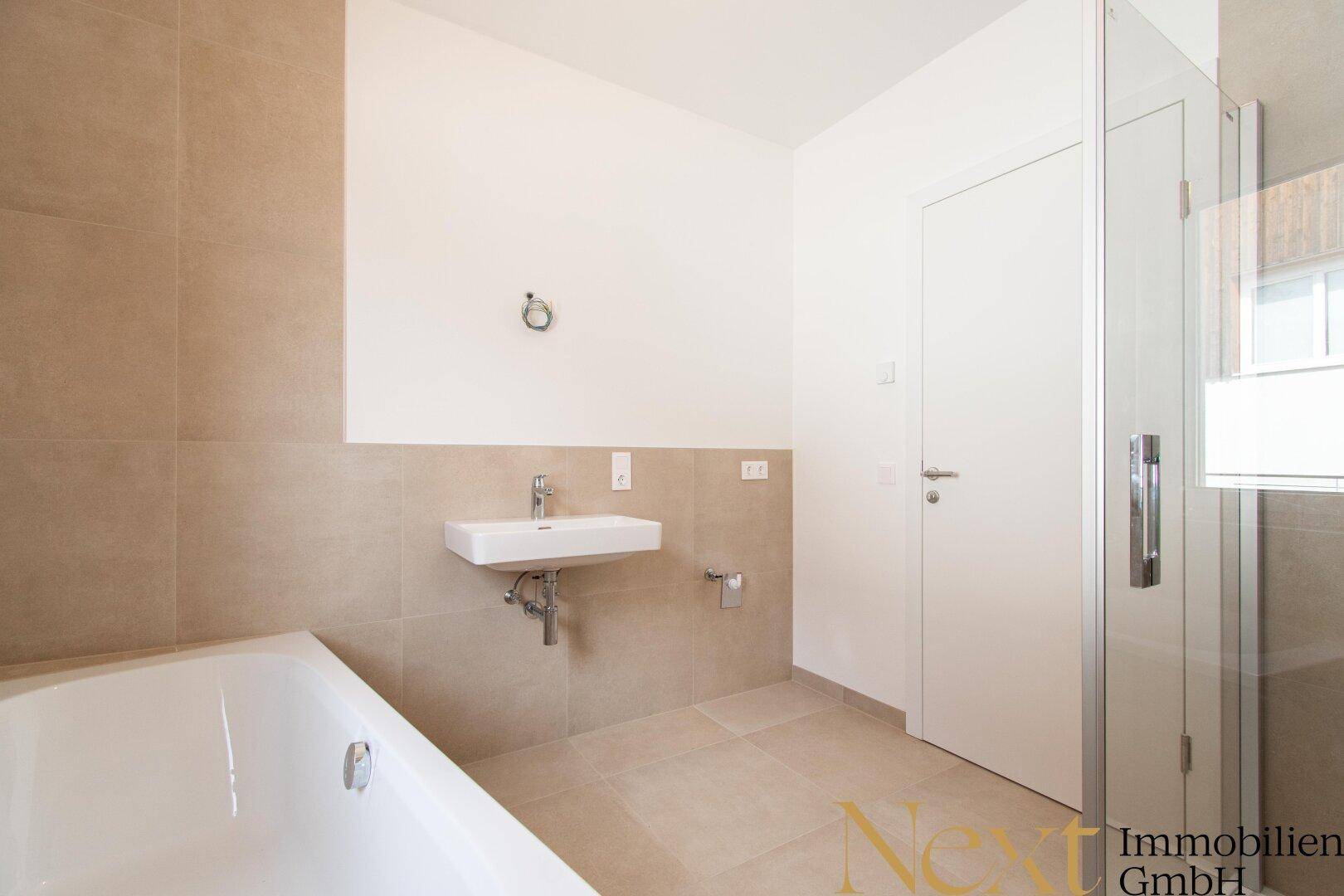 Helles Badezimmer mit Badewanne, Dusche und modernem Waschbecken.