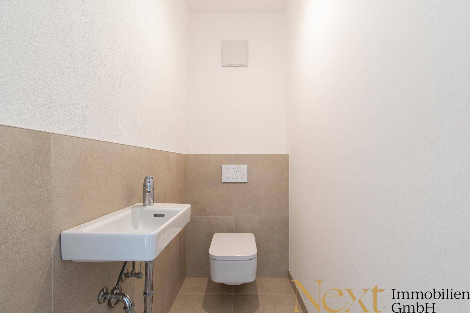 Separates Gäste-WC mit wandhängender Toilette und modernem Waschbecken.