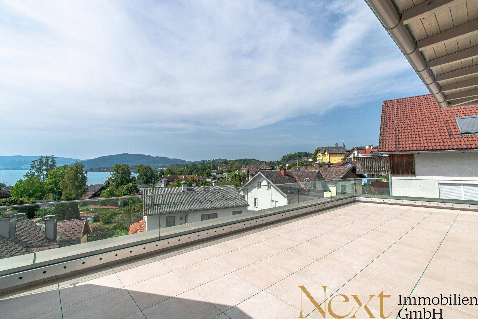 Weitläufige Dachterrasse mit Fliesenboden und Panoramablick auf die Umgebung und den See.