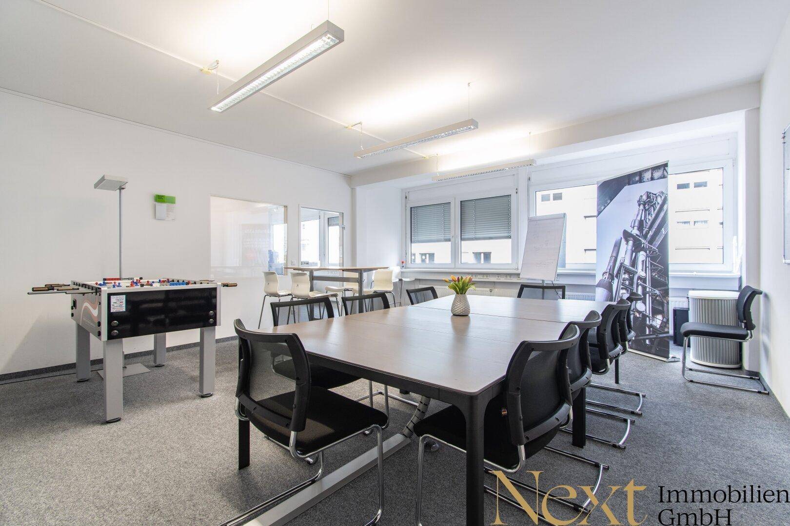 Konferenzraum mit großem Tisch, Stühlen und einem Tischkicker für Pausen und Teambuilding.