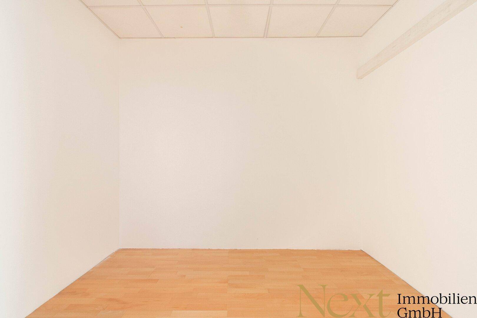 Kleiner, leerer Raum mit hellem Holzfußboden und weißen Wänden, ideal als Einzelbüro oder Abstellraum.