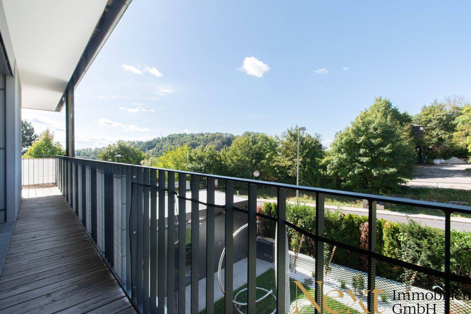 Balkon mit Holzboden und Blick auf die grüne Umgebung, ideal zum Entspannen.