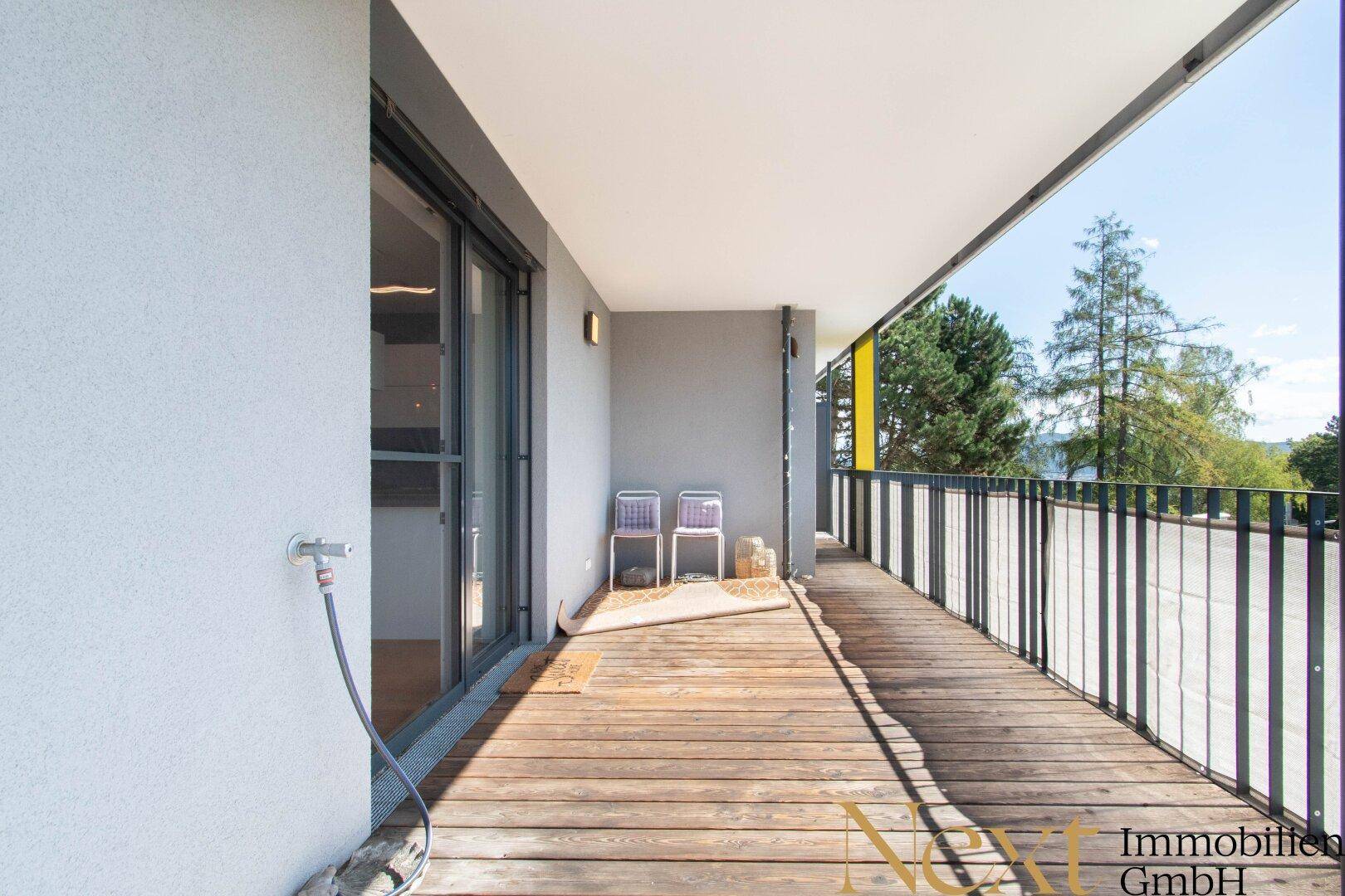 Geräumiger Balkon mit Holzboden und Sitzgelegenheiten, ideal für entspannte Stunden im Freien.
