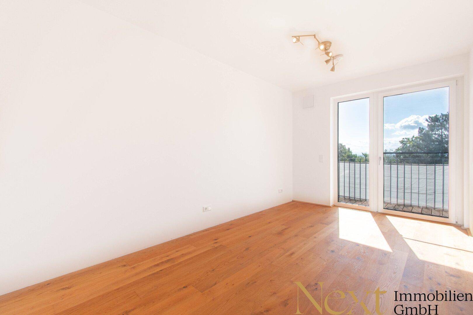 Helles Wohnzimmer mit Holzboden und Zugang zu einem Balkon, bereit zur individuellen Gestaltung.