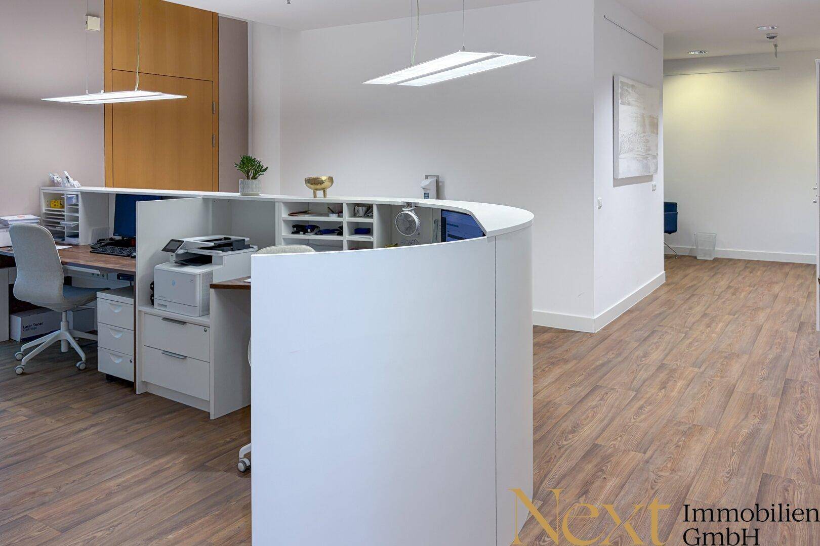Empfangsbereich mit moderner Theke und Arbeitsplatz, ausgestattet mit Drucker und Ablageflächen.