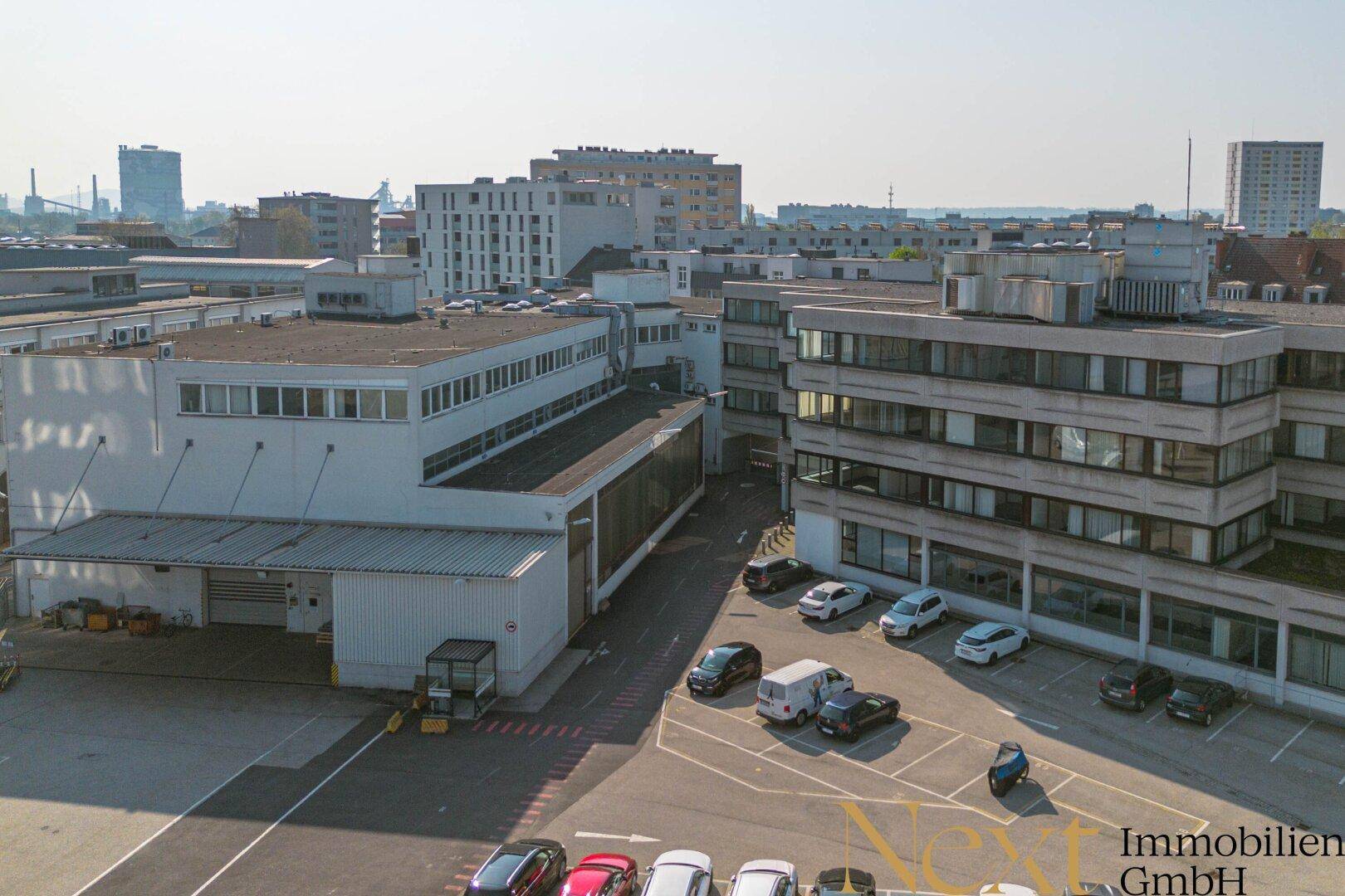 Luftaufnahme eines großen Gewerbekomplexes mit Parkplätzen und mehreren Gebäuden in einer Industriezone.