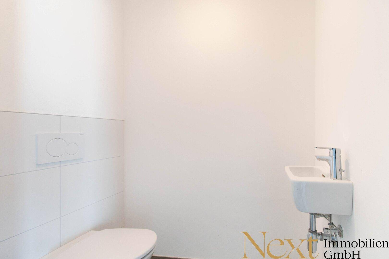 Funktionales Gäste-WC mit wandhängender Toilette und kleinem Handwaschbecken.