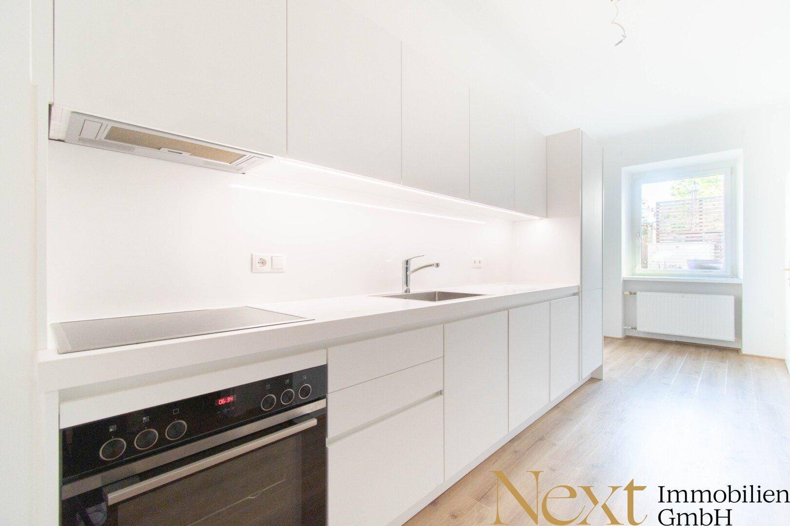 Moderne, helle Einbauküche mit weißen Fronten, Induktionskochfeld und Backofen.