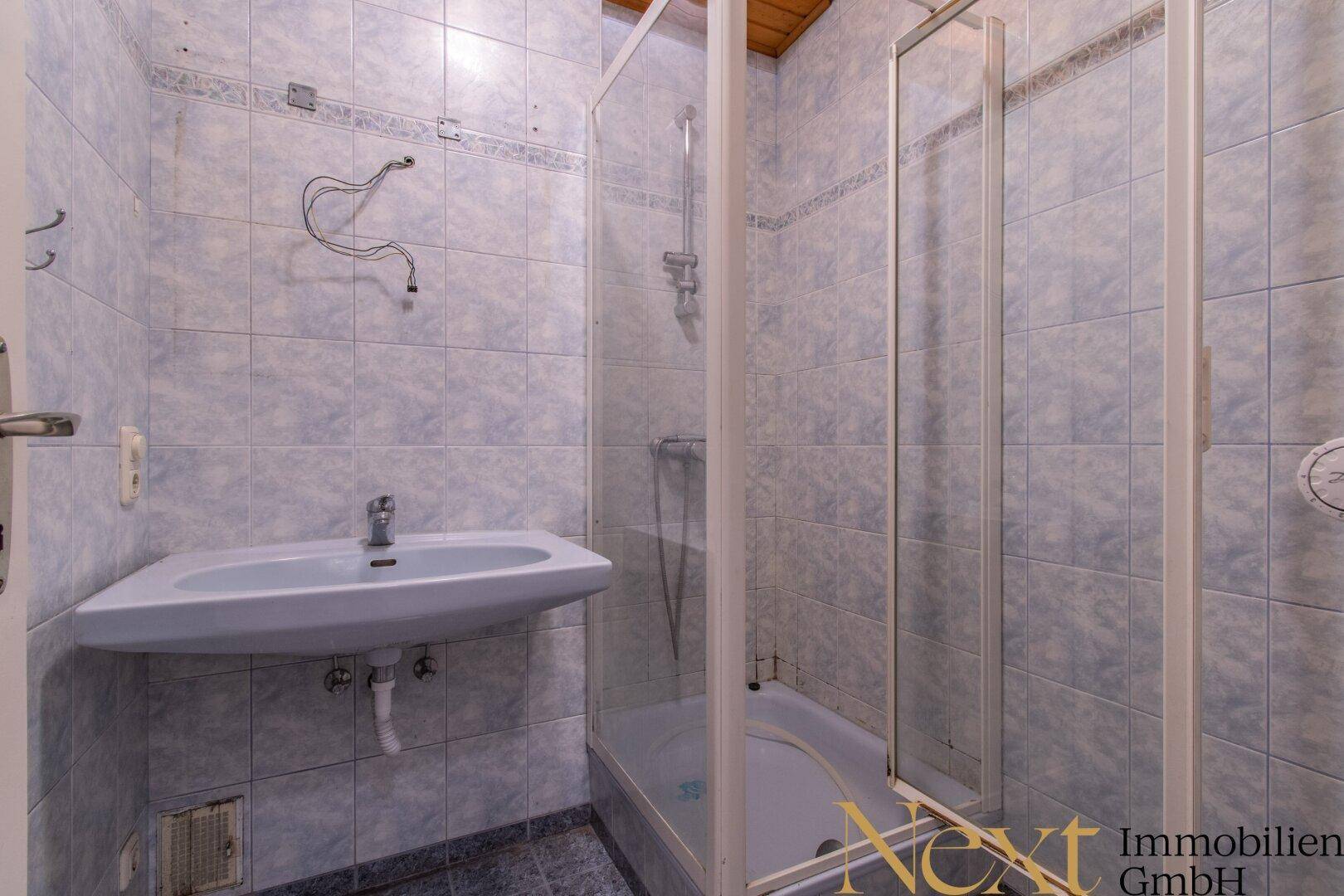 Badezimmer mit blauen Fliesen, Dusche und Einzelwaschbecken.