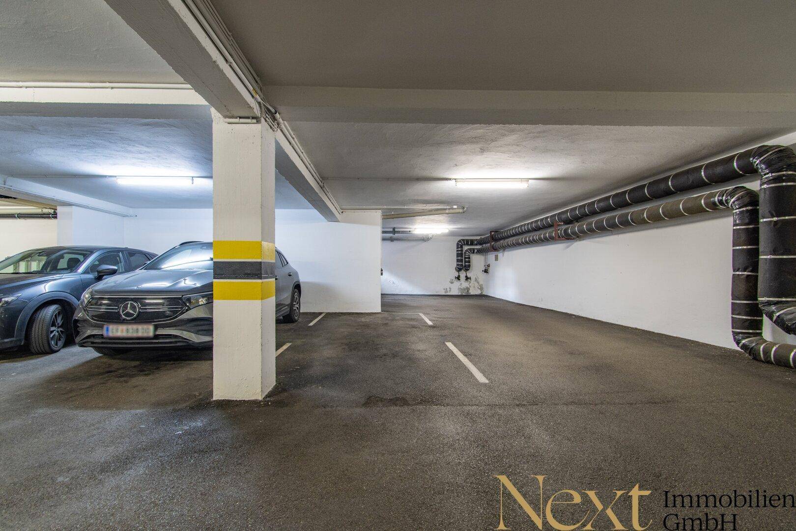 Helle Tiefgarage mit mehreren Stellplätzen, funktionaler Beleuchtung und sauberem Betonboden.