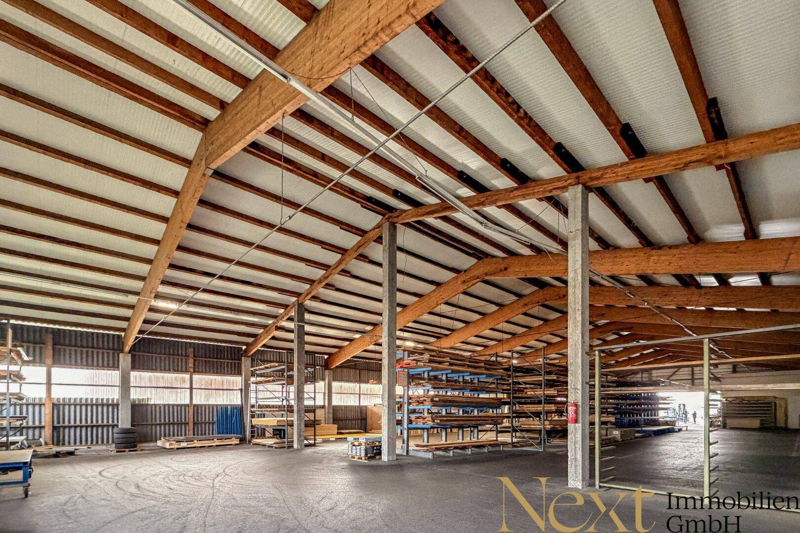 Weitläufige Lagerhalle mit hoher Decke, Holzkonstruktion und viel Platz für Lagerung und Betrieb.