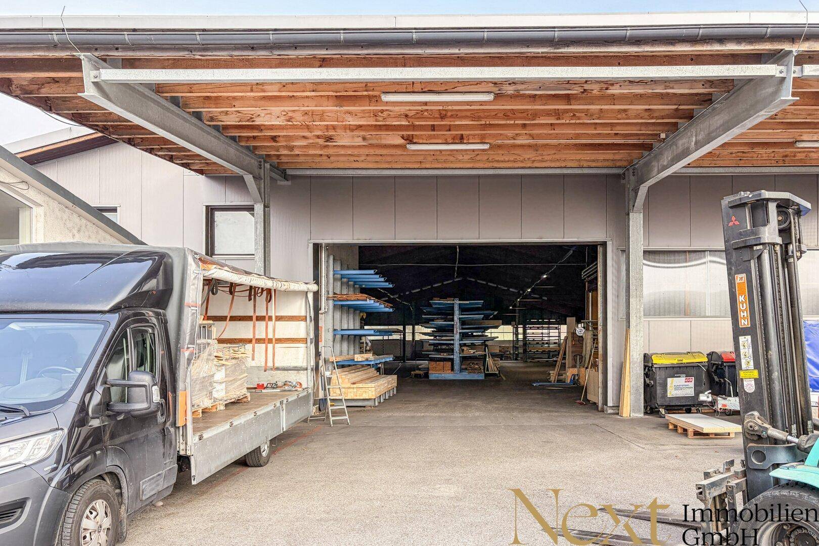 Ladebereich einer Lagerhalle mit überdachter Rampe, offenem Tor und einem Lieferwagen davor.