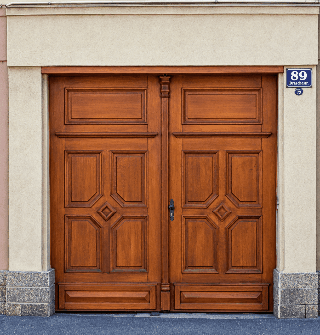 Große, reich verzierte Holztür mit Hausnummer und Straßennamen an einer Fassade.