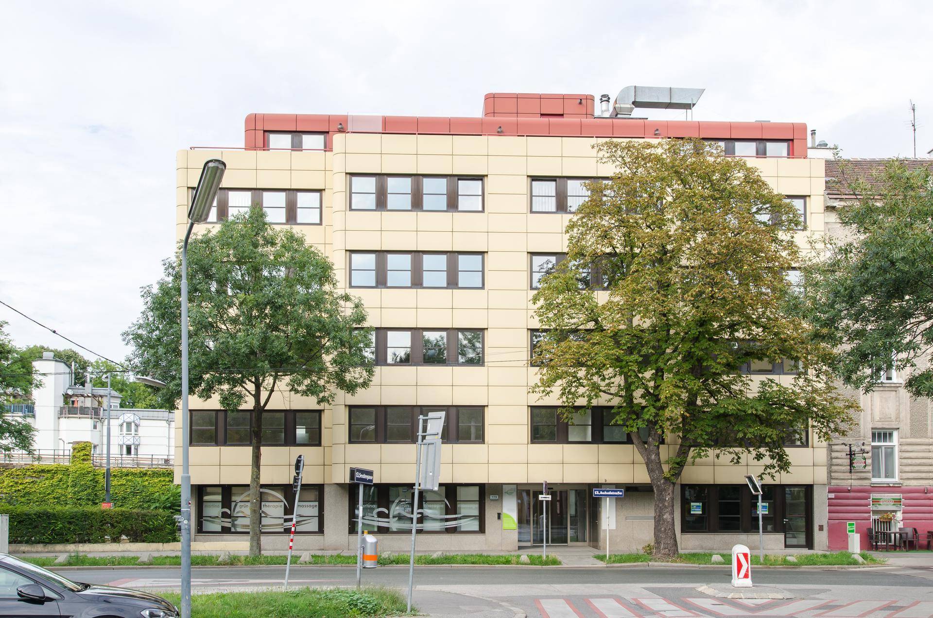 Außenansicht eines modernen Bürogebäudes mit gelber Fassade und großen Fenstern an einer Straße.