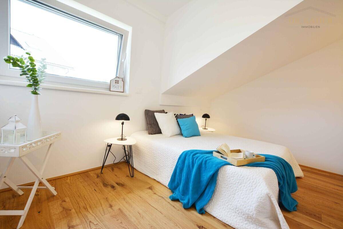 Helles Schlafzimmer mit Holzboden, einem Bett und einem großen Fenster.
