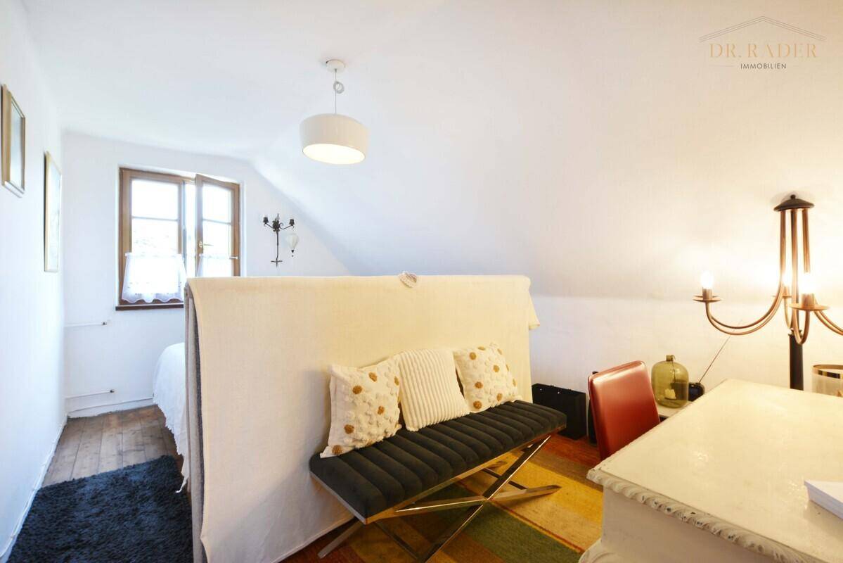 Gemütliches Schlafzimmer im Dachgeschoss mit schräger Decke und Holzboden.