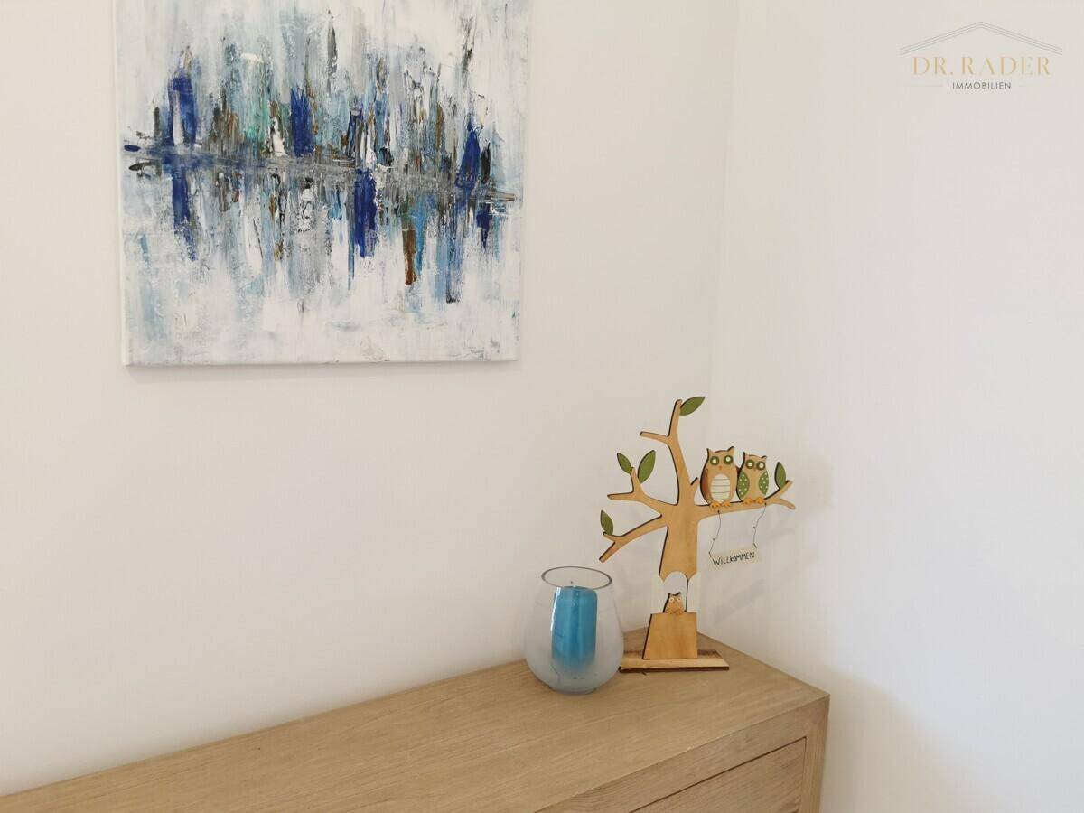 Dekorative Elemente mit modernem Kunstwerk und Holzkommode in hellem Raum.