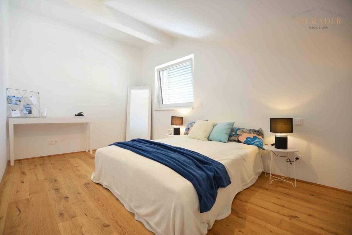 Helles Schlafzimmer mit Holzboden, Doppelbett und schrägen Decken im Dachgeschoss.