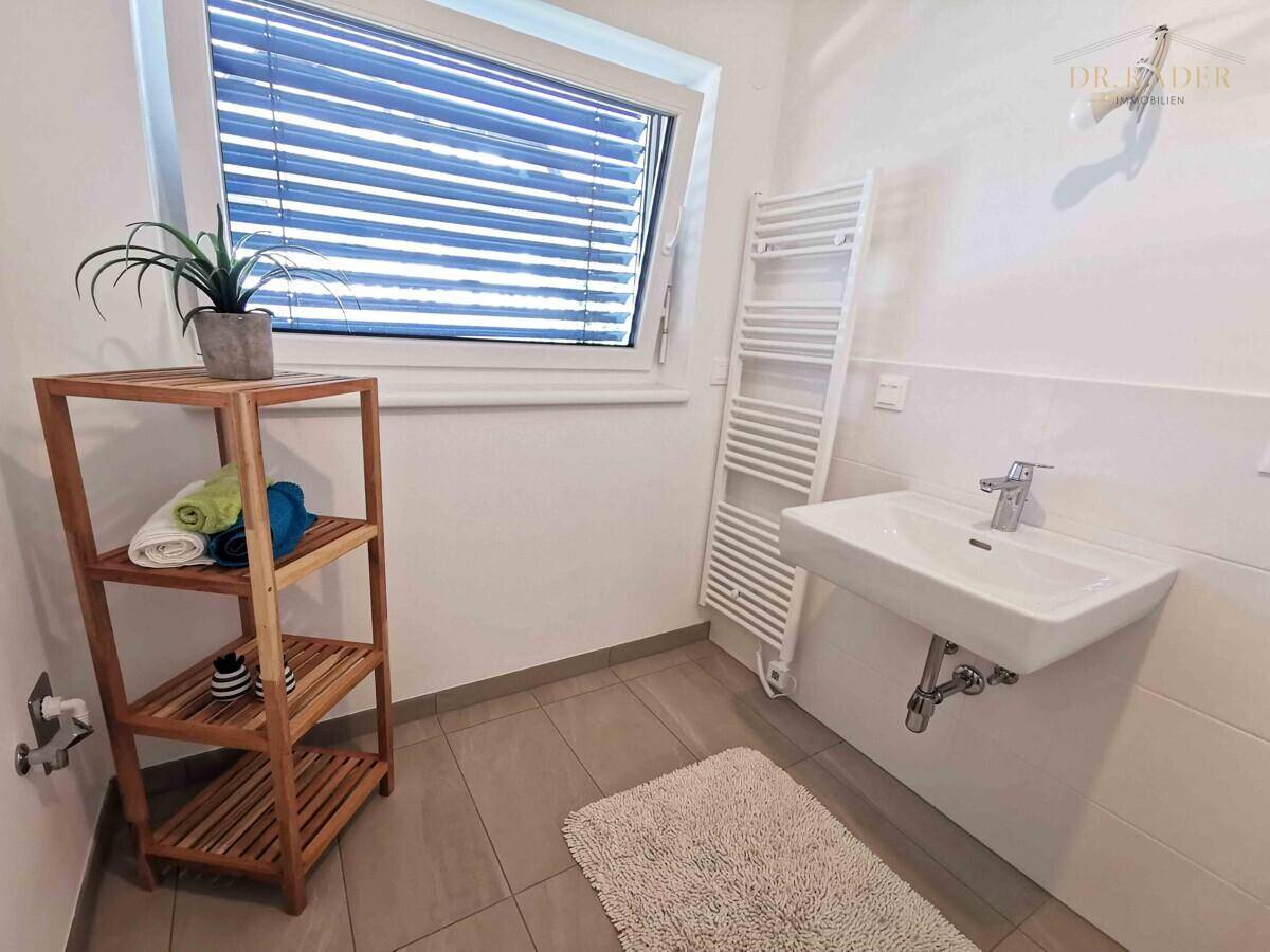 Modernes Badezimmer mit Waschbecken, beheiztem Handtuchhalter und Fenster.
