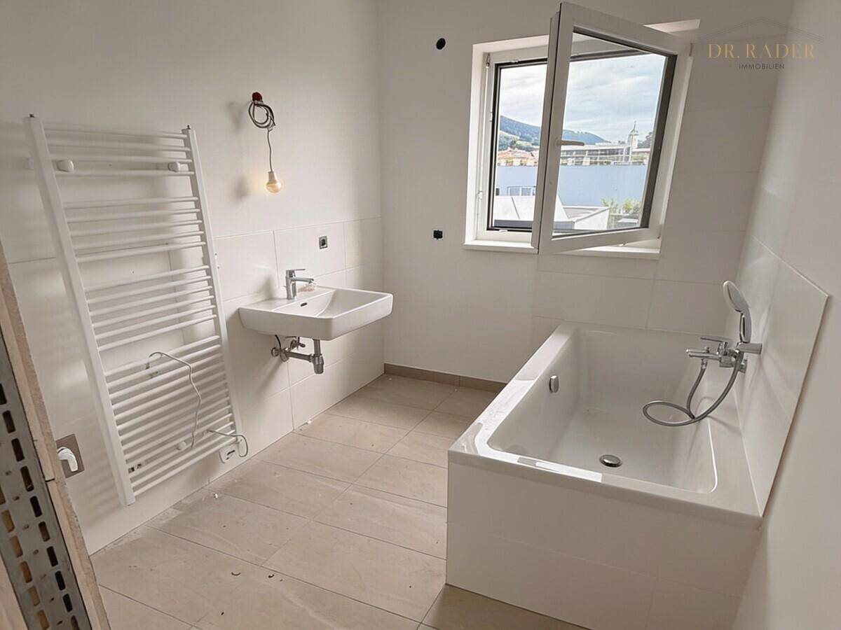 Modernes Badezimmer im Bau mit Badewanne, Waschbecken und Fenster, bereit zur Fertigstellung.