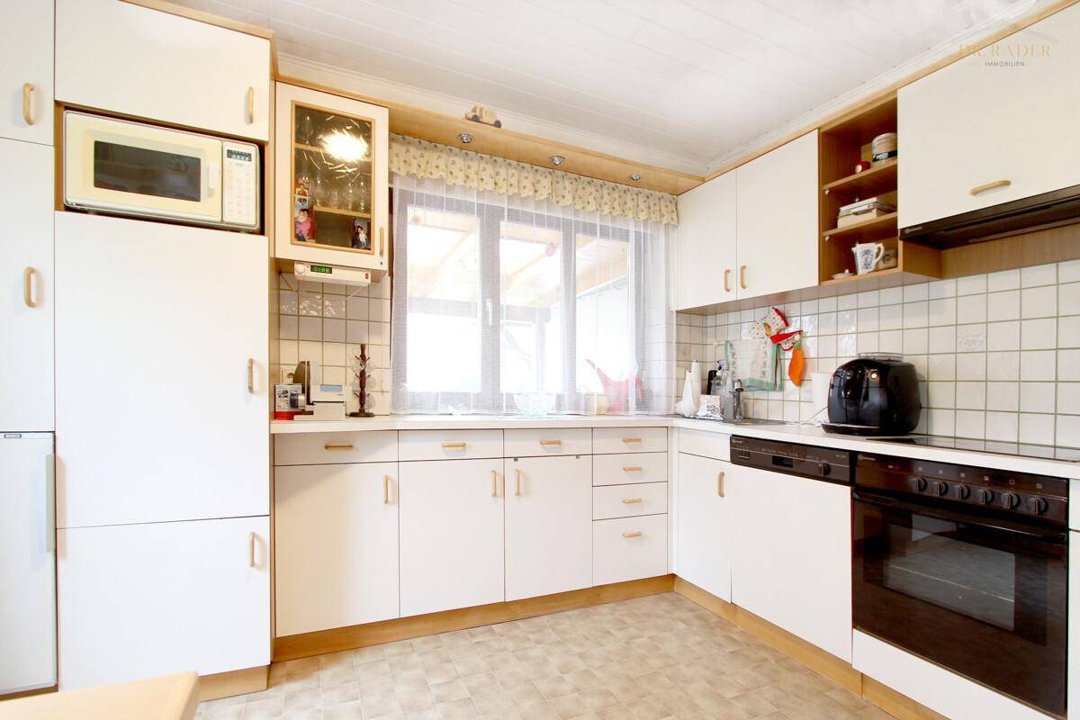 Funktionale Küche mit weißen Schränken, integrierten Geräten und Fenster.