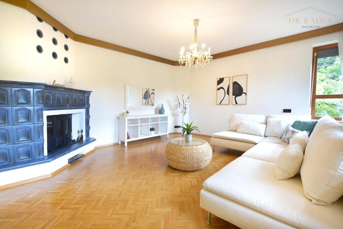 Gemütliches Wohnzimmer mit traditionellem Kachelofen, hellem Parkettboden und moderner Einrichtung.