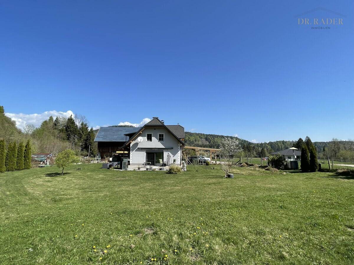 Weitläufiges Grundstück mit Einfamilienhaus und Blick auf die umliegende Naturlandschaft.