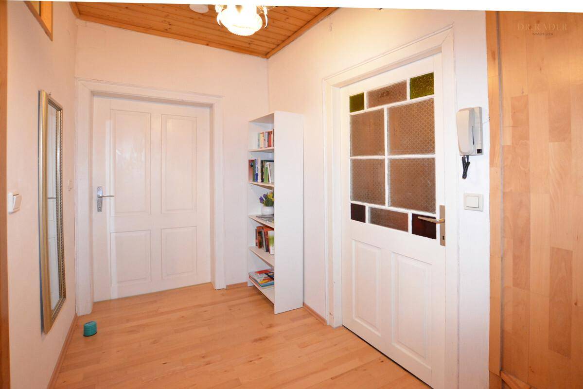 Heller Flur mit Holzboden, weißer Tür und dekorativem Glaseinsatz.
