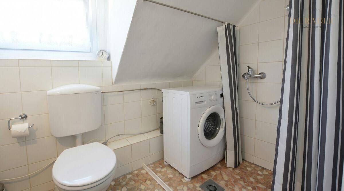 Badezimmer im Dachgeschoss mit Dusche, WC und Waschmaschine unter der Schräge.