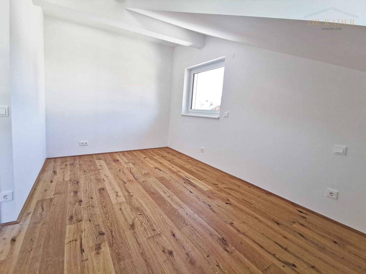 Helles Schlafzimmer im Dachgeschoss mit Holzboden und schrägen Wänden, bereit zur Einrichtung.