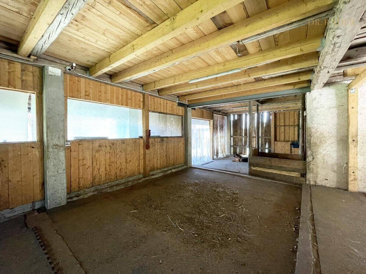 Rustikaler Innenraum eines Holzgebäudes mit sichtbaren Balken und Holzverkleidung.