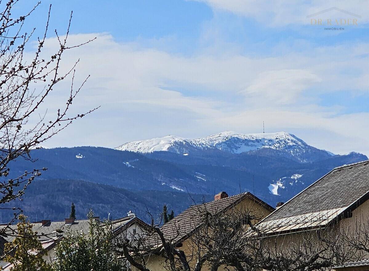 Panoramablick auf schneebedeckte Berge über den Dächern der umliegenden Häuser.