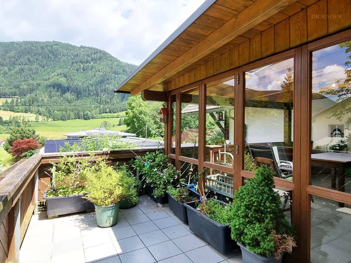 Überdachter Balkon mit Sitzgelegenheiten und weitem Blick auf die Berge.
